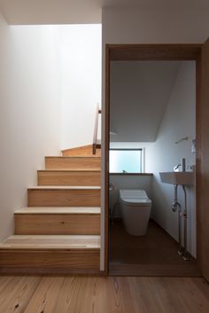 there is a toilet and some stairs in this bathroom with wood flooring on both sides