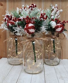 three mason jars filled with red and white flowers