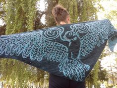 a woman is holding up a shawl that has an image of an owl on it