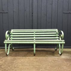 a green bench sitting in front of a black wall