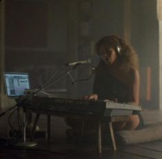 a woman sitting in front of a keyboard with headphones on