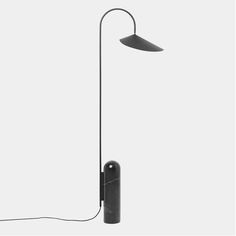 a black floor lamp on a white background with the light turned off and plugged in