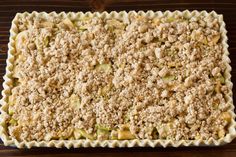 an uncooked casserole with crumbled toppings sits on a wooden surface