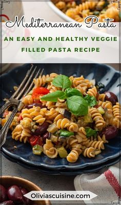 pasta salad with tomatoes, olives and basil on a blue plate next to a fork