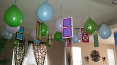 some balloons are hanging from the ceiling in a room with windows and curtains on it