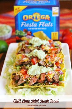 two tacos on a white plate with guacamole and tortilla chips