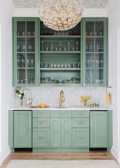 a kitchen with green cabinetry and gold accents on the countertop, along with a chandelier