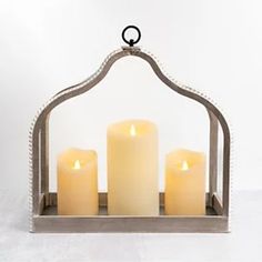 three lit candles in a metal holder