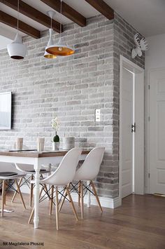 a dining room with white chairs and a brick wall