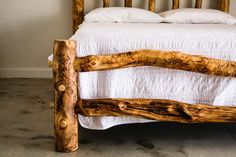 a bed made out of logs and white sheets