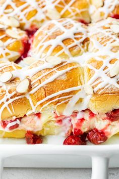 strawberry shortcakes with white icing and almonds in a baking dish on a table