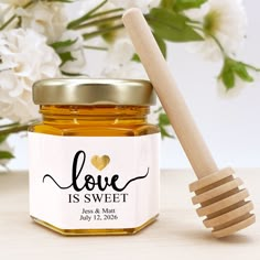 a jar of honey with a wooden spoon next to it and flowers in the background