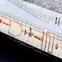 an aerial view of people walking on a walkway near the water's edge with orange barricades