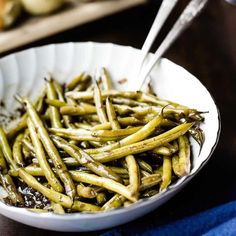 a white bowl filled with green beans on top of a table