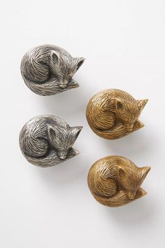 three silver and gold animal knobs sitting on top of a white surface with one laying down