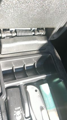 the inside of a car with tools in it's storage compartment and other items