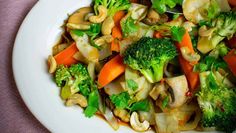 a white plate topped with broccoli, carrots and other veggies