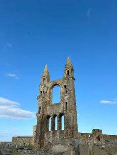 an old stone building with two towers on the top and one at the bottom, against a blue sky