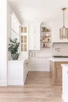 a large kitchen with white cabinets and wood flooring is seen in this image from the doorway