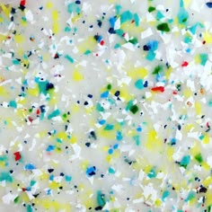 colorful confetti sprinkles are scattered on a white surface with blue, yellow, red, and green colors