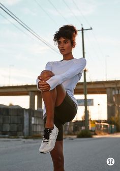 a woman in white shirt and black shorts doing a kickbox pose on skateboard