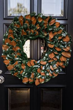 a wreath with orange and green leaves is hanging on the front door