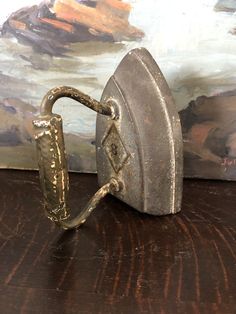 an old iron sitting on top of a wooden table next to a wall with a painting behind it