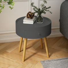 a small round table with a plant on top and a book sitting on the end