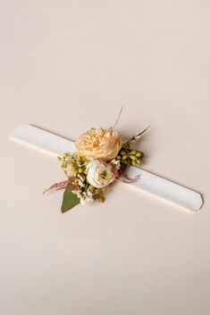 a boutonniere with flowers and greenery on the top is laying on a white surface