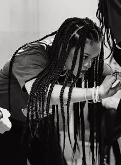 a woman with dreadlocks is fixing another woman's hair in a black and white photo