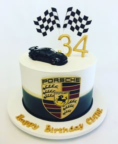 a birthday cake with a racing car on top and the number 34 written in gold