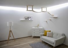 a living room with white walls and wooden floors is lit by recessed lights above the couch