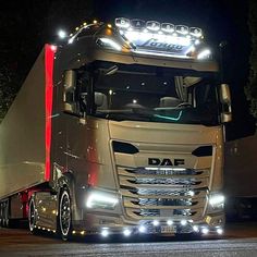 a large semi truck driving down a street at night