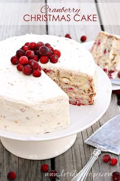 a white cake with cranberries on top and one slice missing from the cake