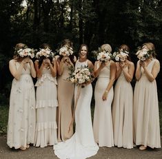 a group of women standing next to each other wearing dresses and holding bouquets in their hands