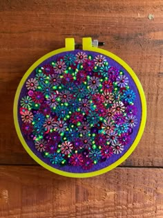 a purple and yellow circular object with colorful flowers on the inside, sitting on a wooden surface