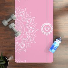 a yoga mat and water bottle sitting on a wooden floor next to a pair of dumbbells