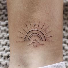 a woman's foot with a sun and wave tattoo on the side of her leg