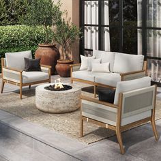 an outdoor living room with white couches and chairs around a fire pit in the center