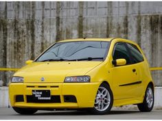 a yellow car parked in front of a concrete wall