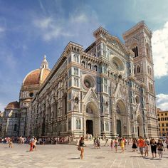 people are walking around in front of a large building that has many windows and arches