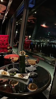 a table with food and drinks on it in front of a window overlooking the water