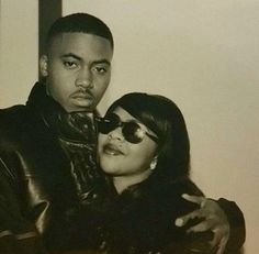 a black and white photo of a man and woman posing for the camera with their arms around each other