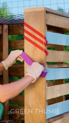 a man is painting the side of a wooden structure with paint and tape on it