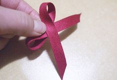 a hand holding a pink ribbon on top of a table