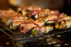 bacon wrapped jalapenos sitting on top of a metal rack