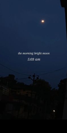 the moon is shining brightly in the night sky over some buildings and telephone poles with an inscription on it