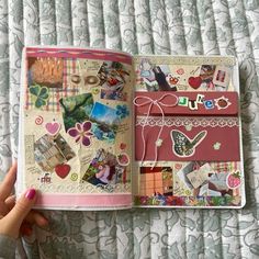 a hand holding an open book on top of a bed covered in lots of stickers