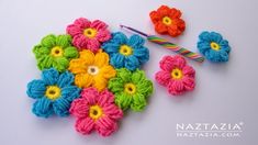 crochet flowers and pins on a white surface