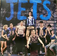 a group of young men standing next to each other in front of a graffiti covered wall